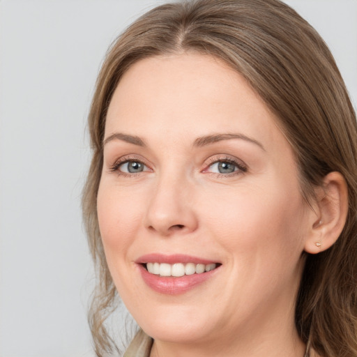 Joyful white adult female with long  brown hair and grey eyes