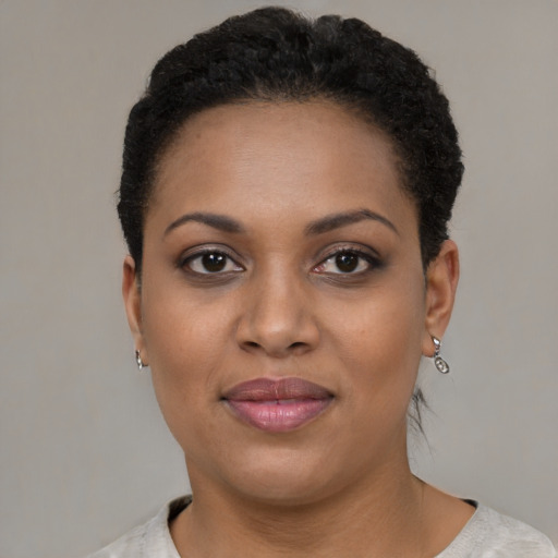 Joyful black young-adult female with short  black hair and brown eyes