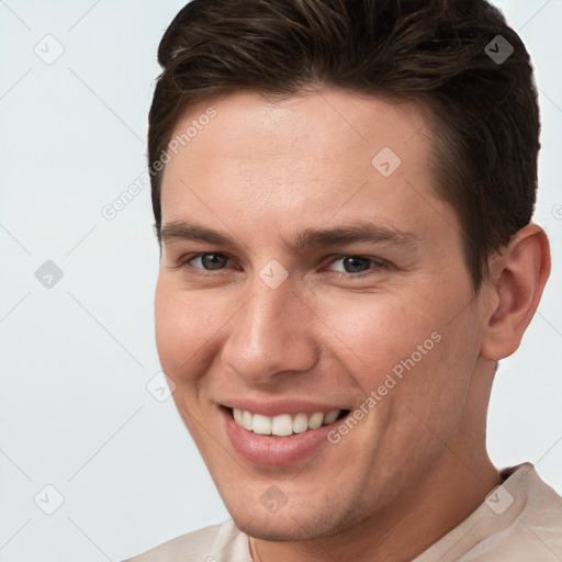 Joyful white young-adult male with short  brown hair and grey eyes