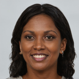 Joyful black adult female with medium  brown hair and brown eyes