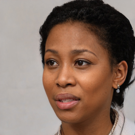 Joyful black young-adult female with short  black hair and brown eyes