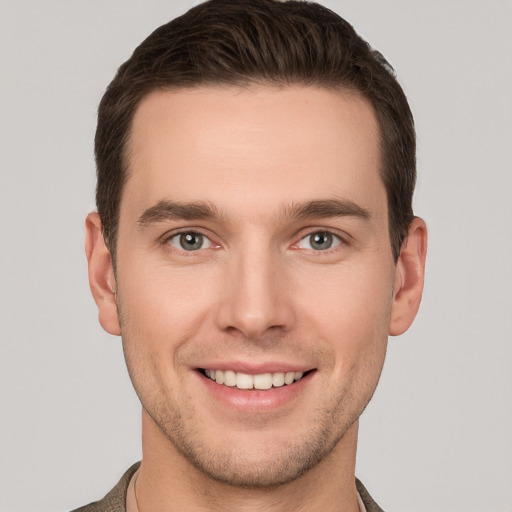 Joyful white young-adult male with short  brown hair and grey eyes