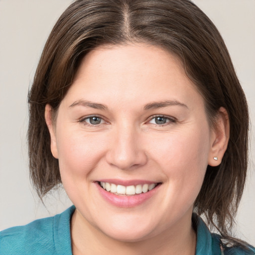 Joyful white young-adult female with medium  brown hair and grey eyes