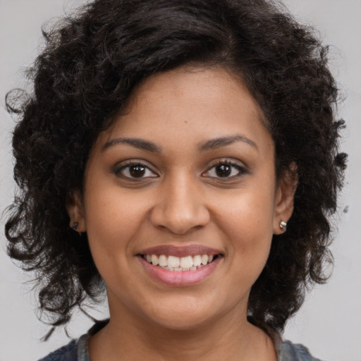 Joyful black young-adult female with long  brown hair and brown eyes