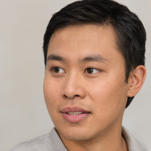 Joyful asian young-adult male with short  black hair and brown eyes