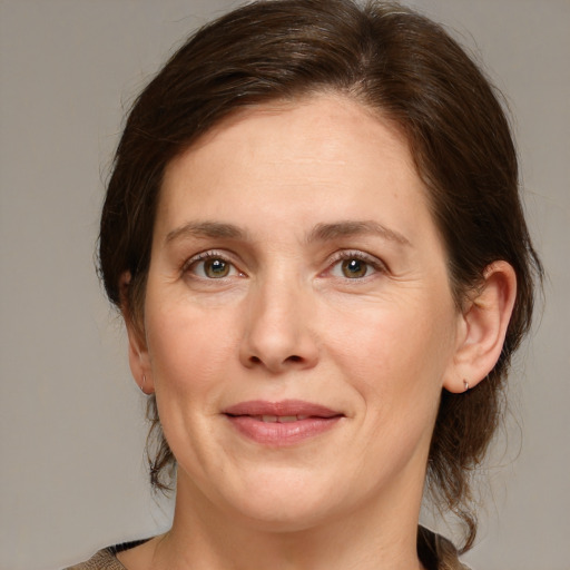 Joyful white adult female with medium  brown hair and green eyes