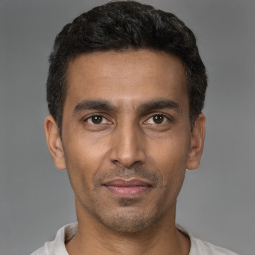 Joyful latino young-adult male with short  brown hair and brown eyes