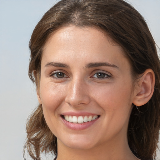 Joyful white young-adult female with medium  brown hair and grey eyes