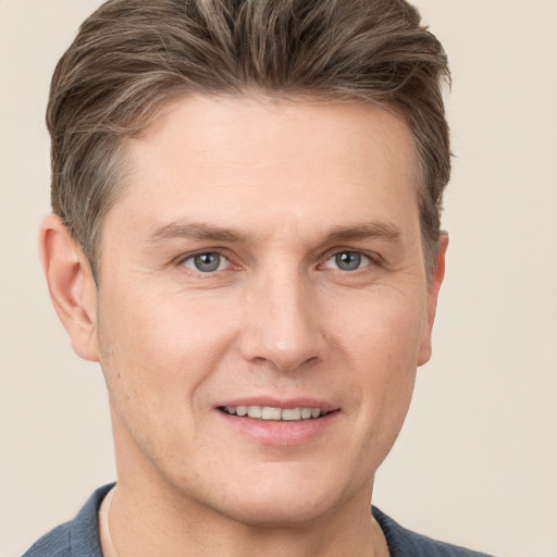 Joyful white young-adult male with short  brown hair and grey eyes