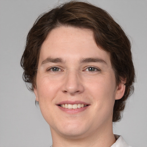 Joyful white young-adult male with medium  brown hair and grey eyes