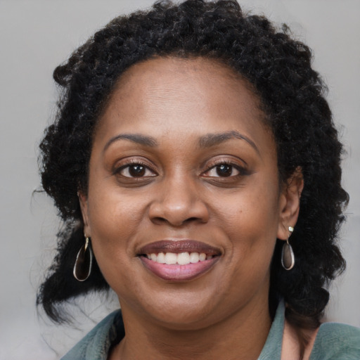 Joyful black adult female with long  brown hair and brown eyes