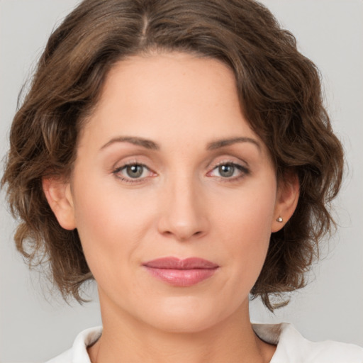 Joyful white young-adult female with medium  brown hair and grey eyes