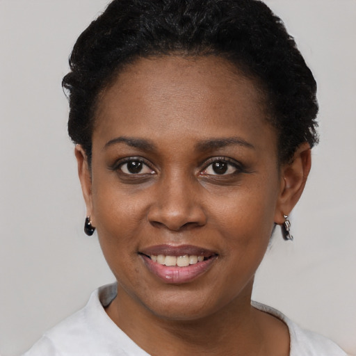 Joyful black young-adult female with short  black hair and brown eyes