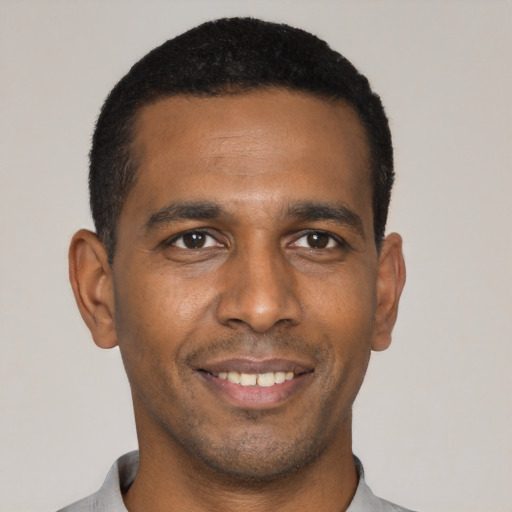 Joyful black young-adult male with short  black hair and brown eyes