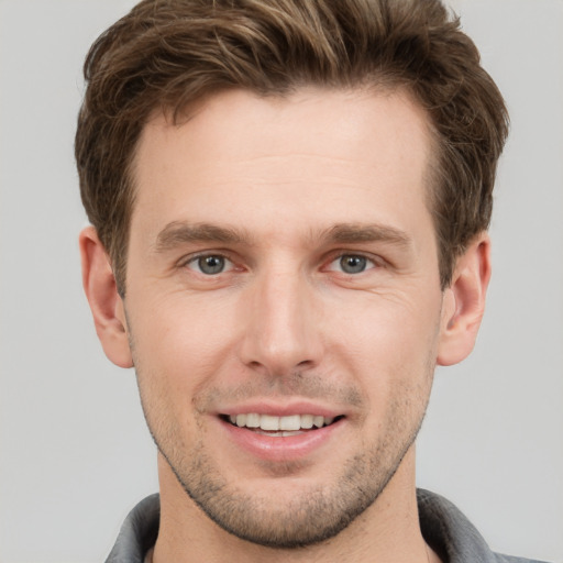 Joyful white young-adult male with short  brown hair and grey eyes