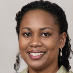 Joyful black young-adult female with long  brown hair and brown eyes