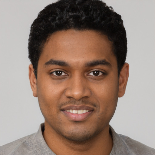 Joyful black young-adult male with short  black hair and brown eyes