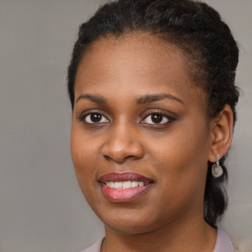 Joyful black young-adult female with long  brown hair and brown eyes