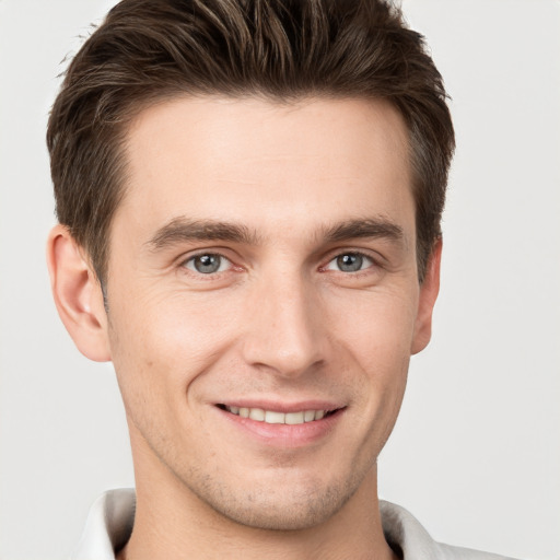 Joyful white young-adult male with short  brown hair and grey eyes