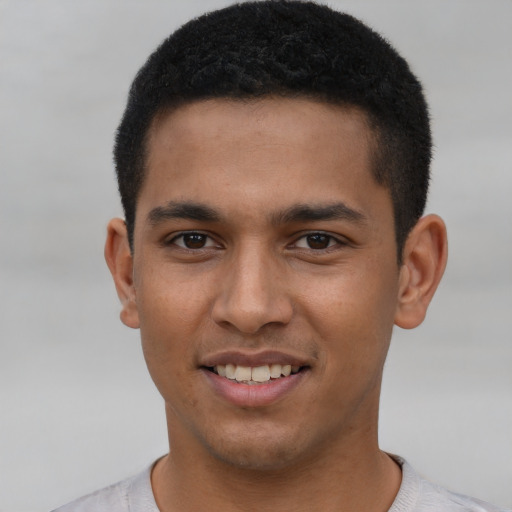 Joyful black young-adult male with short  brown hair and brown eyes
