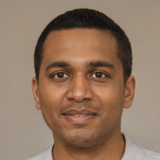 Joyful black young-adult male with short  black hair and brown eyes