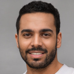 Joyful latino young-adult male with short  black hair and brown eyes