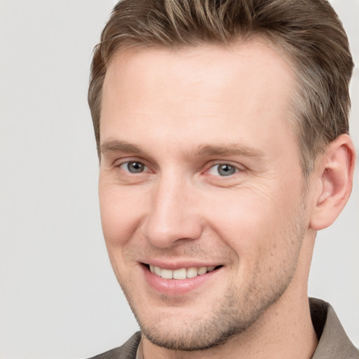 Joyful white young-adult male with short  brown hair and grey eyes