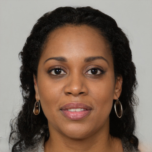 Joyful black young-adult female with long  brown hair and brown eyes