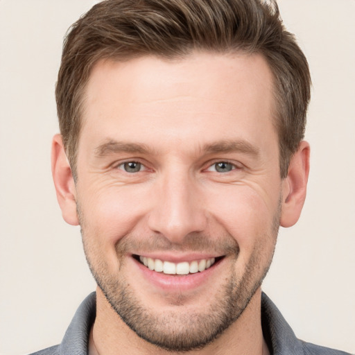 Joyful white young-adult male with short  brown hair and grey eyes