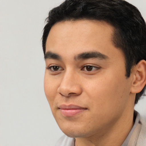 Joyful latino young-adult male with short  black hair and brown eyes
