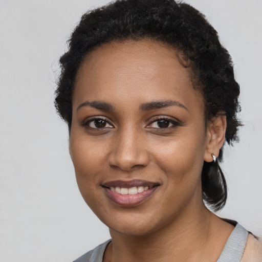 Joyful black young-adult female with short  black hair and brown eyes