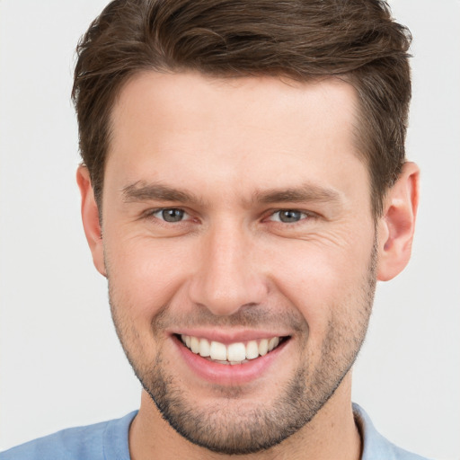 Joyful white young-adult male with short  brown hair and grey eyes