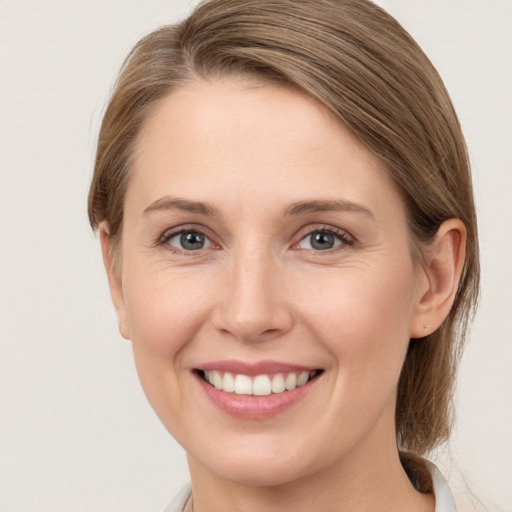 Joyful white young-adult female with medium  brown hair and grey eyes