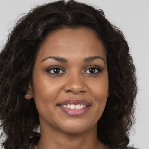 Joyful black young-adult female with long  brown hair and brown eyes