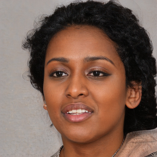 Joyful black young-adult female with long  black hair and brown eyes