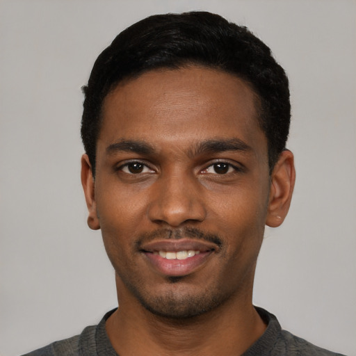 Joyful black young-adult male with short  black hair and brown eyes