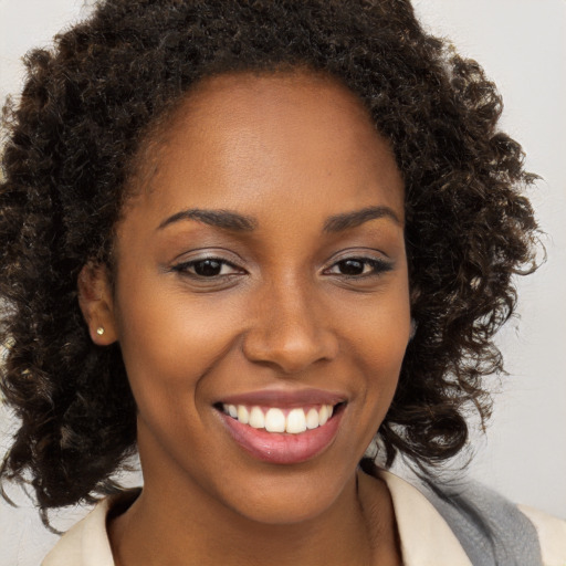 Joyful black young-adult female with long  brown hair and brown eyes