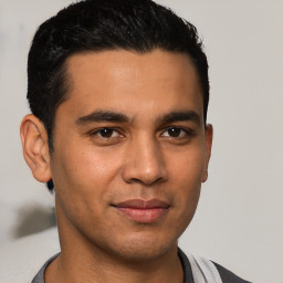 Joyful latino young-adult male with short  black hair and brown eyes