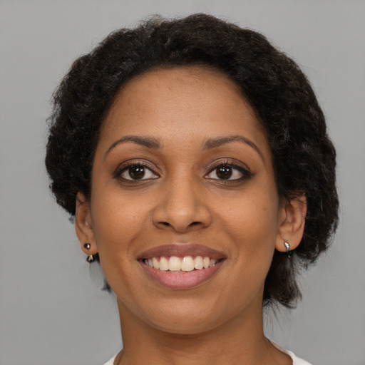 Joyful black young-adult female with short  brown hair and brown eyes