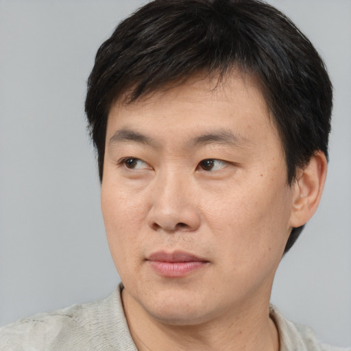Joyful asian young-adult male with short  brown hair and brown eyes