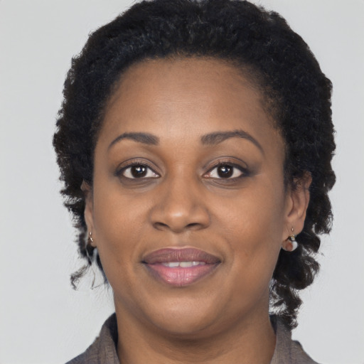 Joyful black young-adult female with long  brown hair and brown eyes