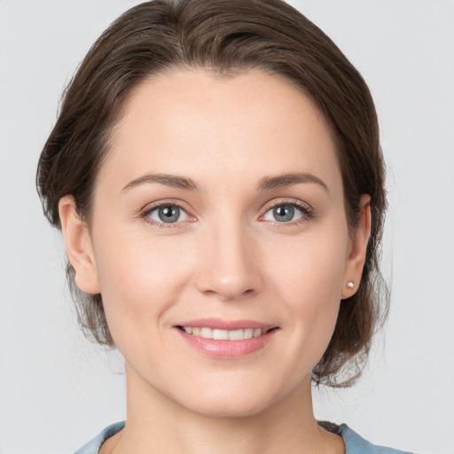 Joyful white young-adult female with medium  brown hair and grey eyes