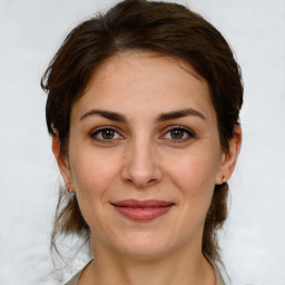 Joyful white young-adult female with medium  brown hair and grey eyes