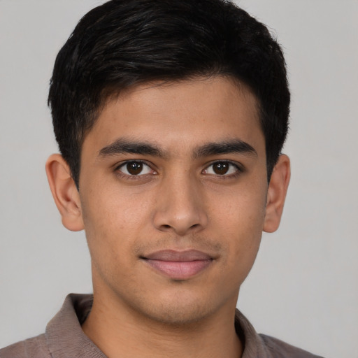 Joyful latino young-adult male with short  brown hair and brown eyes