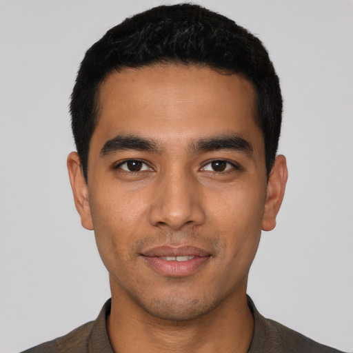 Joyful latino young-adult male with short  black hair and brown eyes