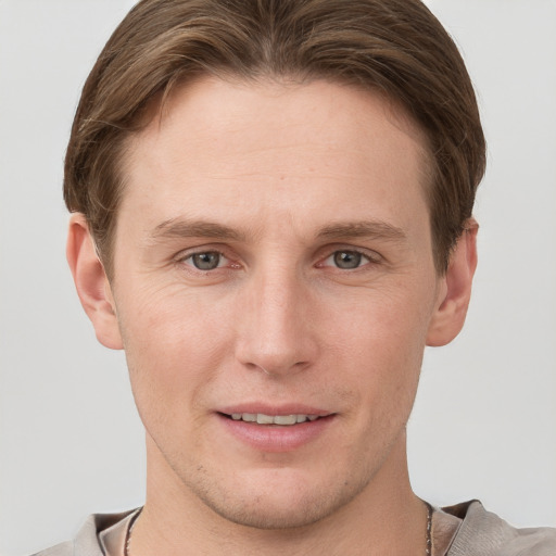 Joyful white young-adult male with short  brown hair and grey eyes