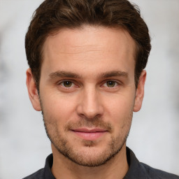 Joyful white young-adult male with short  brown hair and grey eyes