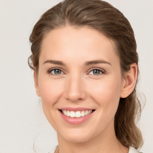 Joyful white young-adult female with medium  brown hair and grey eyes