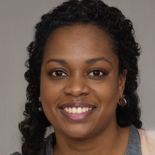 Joyful black young-adult female with long  black hair and brown eyes