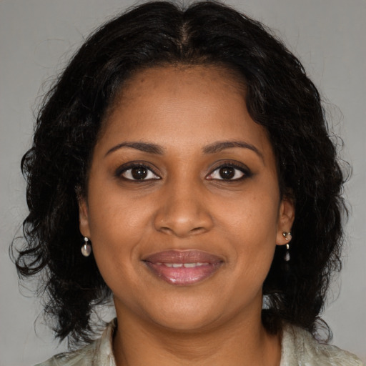 Joyful black young-adult female with long  brown hair and brown eyes